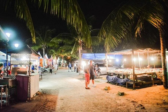 Bancarelle di cibo illuminate lungo un sentiero sul mare di notte